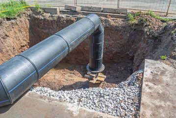 Large diameter plastic pipe for water supply. A smooth black plastic pipe with a blue stripe is...