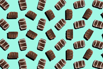 Top view of assorted chocolate pralines with decorative lines on a turquoise background