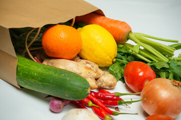 Reusable paper bag with spilled fresh vegetables and fruits on white background. Eco-friendly, plastic-free, zero waste lifestyle concept.