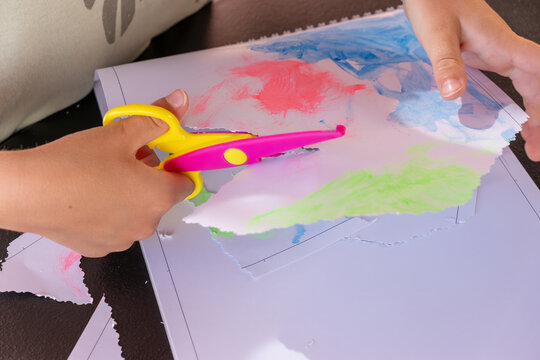 6-7 years child using colorful and wavy scissors is cutting colorful paper, creating crafts for back to school activities