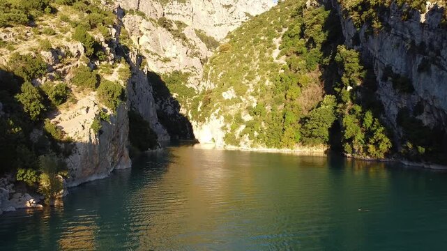 Two people paddle a kayak through a scenic canyon lake surrounded by cliffs. Kayaking and adventure idea. Nature and travel concept.