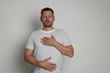 Panic attack. Man breathing to calm down on light grey background