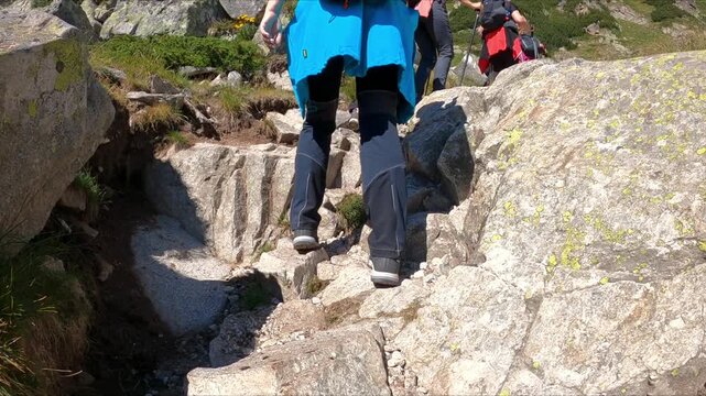 Slow motion of the hikers climb a steep rocky trail in the mountains. Hiking and adventure idea. Nature and outdoor concept.