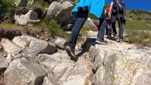 Slow motion of the hikers climb a steep rocky trail in the mountains. Hiking and adventure idea. Nature and outdoor concept.