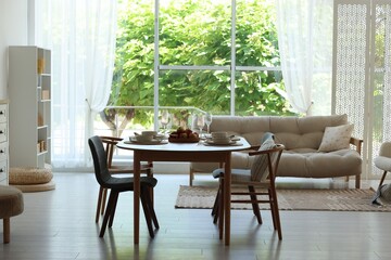Beautiful table setting, chairs and decor in dining room. Interior design