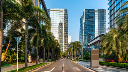 Modern city street with tall glass buildings and palm trees