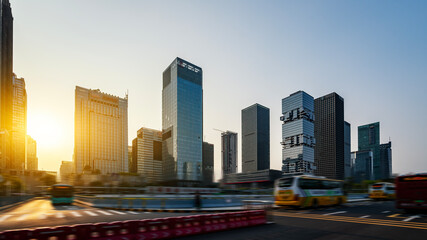 Urban cityscape with modern buildings and moving vehicles at sunset