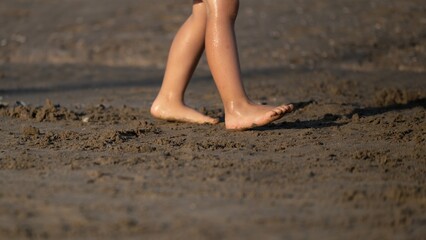 Child s bare feet walking on wet sandy beach