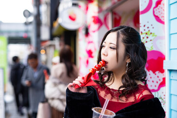 都会の路地でいちご飴を食べる日本人女性のポートレート