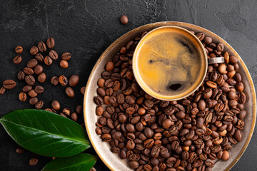 Coffee background - cup of black coffee, coffee beans on a black background top view