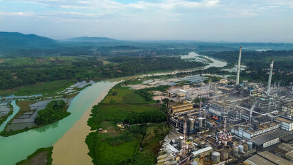 Aerial drone view of a large industrial factory complex with warehouses, chimneys, and storage tanks in Asia