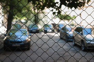chain link fence, cars in the parking lot in the background