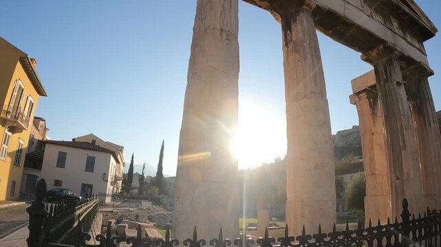 Walking past ancient columns of the Greek columns during golden hour. Historic architecture and travel video idea. Ancient Greece and holidays concept.