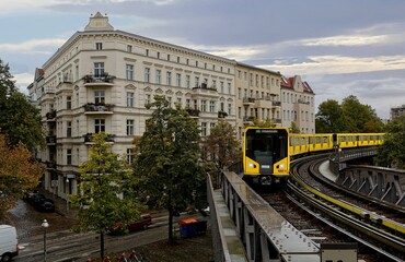 View of a yellow metro train passing thru a curve of the elevated tracks before arriving at...