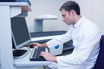 Medical scanner console showing blank monitor and featuring mouse beside keyboard near patient bed