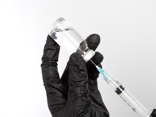 Close-up of a doctor, nurse, or scientist filling or drawing a syringe with medication from a vial....