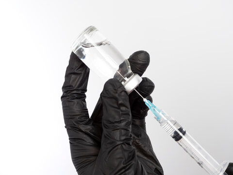 Close-up of a doctor, nurse, or scientist filling or drawing a syringe with medication from a vial. A doctor wearing a red surgical gown drawing fluid from a vial with copy space. Medical concept. - Powered by Adobe