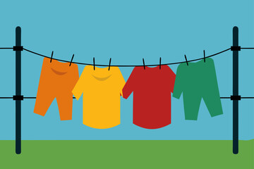Colorful shirts and pants drying on a clothesline against a clear blue sky and green grass