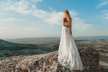 a woman in a white dress, a bride on a mountain with a blue sky. Beautiful nature, freedom,...