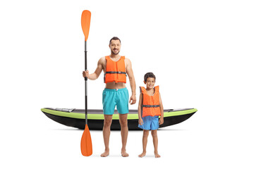 Full length portrait of a father and son with a kayak wearing life jackets and holding a paddle