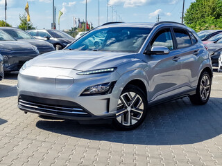 A Sleek and Stylish Silver Electric SUV Positioned in a Modern Car Dealership Setting  Where...