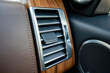 This is a detailed closeup of a sophisticated, modern car air vent that features exquisite wood...