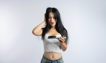 Woman expressing concern over hair loss after brushing holding a hairbrush with hair strands on it