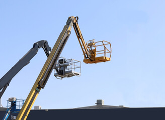 Aerial working platforms of cherry pickers over a flat roof. No people.