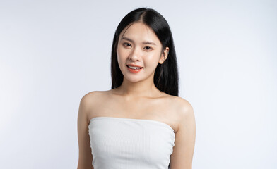 Portrait of a young woman in a white top with long dark hair smiling on a plain background