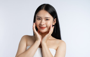 Portrait of a young woman with long dark hair softly touching her face in a studio setting