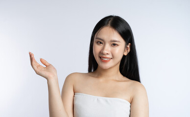 Woman showing open hand presenting gesture long dark hair white tube top bright white backdrop