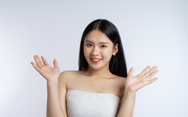 Radiant woman smiling showcasing clear skin with open palms against white backdrop Beauty shot