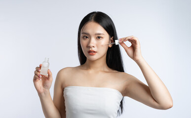 Woman applying serum Using a dropper she is carefully applying product to her face Skincare