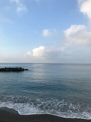 Sunlit sea with reflections of the surrounding hills.
