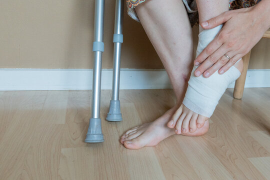 Injured foot with crutches and bandage, recovery and support - Powered by Adobe