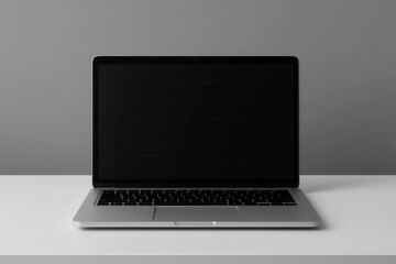 A sleek silver laptop with a blank screen rests on a pristine white desk against a monochromatic backdrop, symbolizing potential and endless possibilities in the digital age