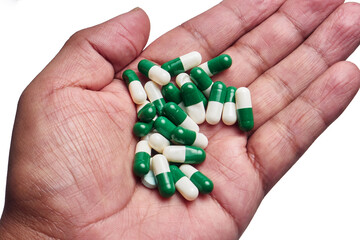 Close up hand cradling assorted green and white capsules with skin texture visible, isolated on...