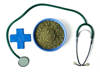 Stethoscope curving around a blue bowl of dried oregano with a medical cross, isolated on white...