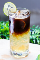 Iced lime coffee in a tall glass, layered with espresso over citrus, served with lime slice garnish and ice cubes.