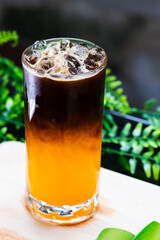 Iced orange coffee in a tall glass, layered with espresso over bright orange juice, served with ice cubes for a refreshing drink.