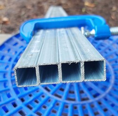 Several aluminum square tubes held together by a blue C clamp metal Cclamp
