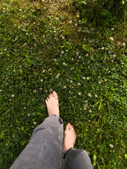 Barefoot woman walking on green grass with small white flowers, enjoying nature and feeling of...
