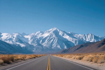 Naklejka premium Vast road stretches towards majestic snow-capped mountains under
