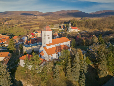 Aerial view of the church towers pierce the skyline, set against the rolling hills and distant mountains, Dobr&Atilde;&iexcl; Niva, Bansk&Atilde;&iexcl; Bystrica Region, Slovakia.