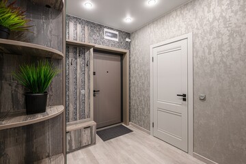 entry way featuring wooden furniture, a door, and textured gray walls. There are plants on the...
