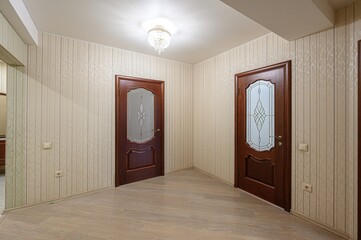 well-lit hallway with two dark wood doors featuring decorative glass panels. The walls are...