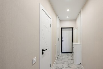 modern hallway featuring neutral walls, marble flooring, a white door with geometric design, and a...