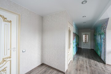 Elegant hallway with white gold doors, textured walls, painted mural, and recessed lighting