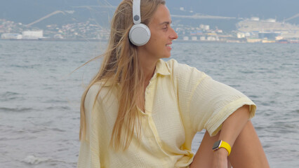 Young Woman Enjoying Music by the Ocean Shore