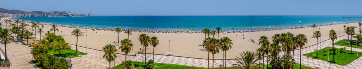 Seafront promenade with the beach full of people enjoying the sand and the sea water